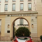 Historic Mandarin Oriental Milan facade with the hotel name above its arched entrance and a red car parked outside