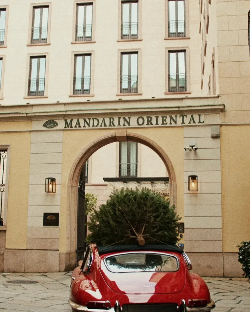 Historic Mandarin Oriental Milan facade with the hotel name above its arched entrance and a red car parked outside