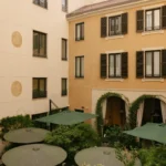 Quiet inner courtyard surrounded by historic hotel buildings with landscaped greenery and outdoor seating at Mandarin Oriental Milan