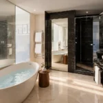 Modern luxury bathroom with a freestanding bathtub, dark marble walls, glass shower and elegant vanity