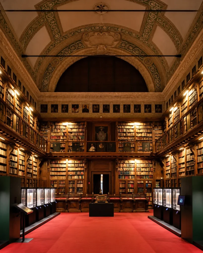 Grand historic library with symmetrical bookshelves, an ornate arched ceiling and a central red carpet