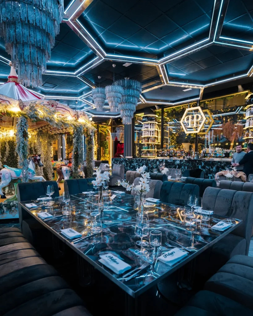 Contemporary restaurant interior with blue accent lighting, geometric ceiling details and elegant dining tables at Philipp's Club Milano