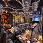 Sophisticated lounge with geometric ceiling lighting, plush chairs and intimate dining tables at Philipp's Club Milano