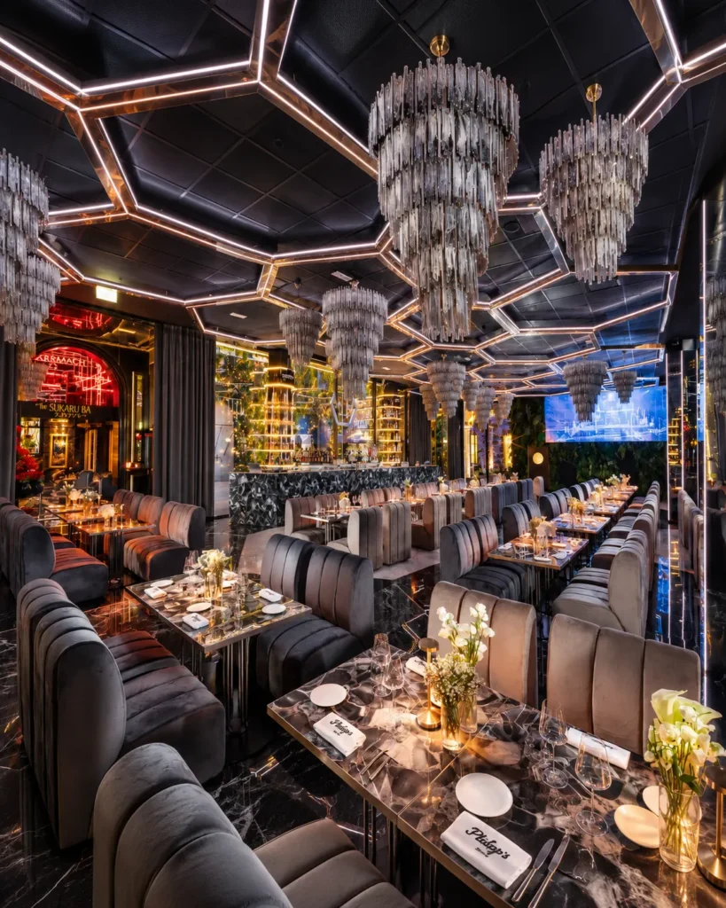 Sophisticated lounge with geometric ceiling lighting, plush chairs and intimate dining tables at Philipp's Club Milano