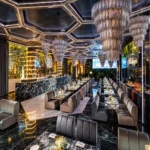Contemporary dining lounge with illuminated hexagonal ceiling panels, plush seating and elegant tables at Philipp's Club Milano