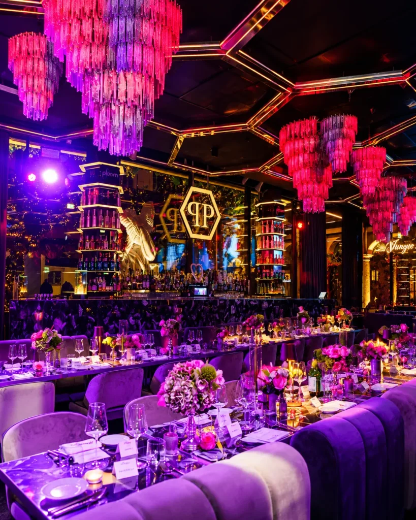 Colorful nightclub dining lounge with purple neon lights, decorative chandeliers and elegant seating at Philipp's Club Milano