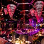 Vibrant dining room with pink neon lighting, decorative chandeliers and elegant restaurant tables at Philipp's Club Milano