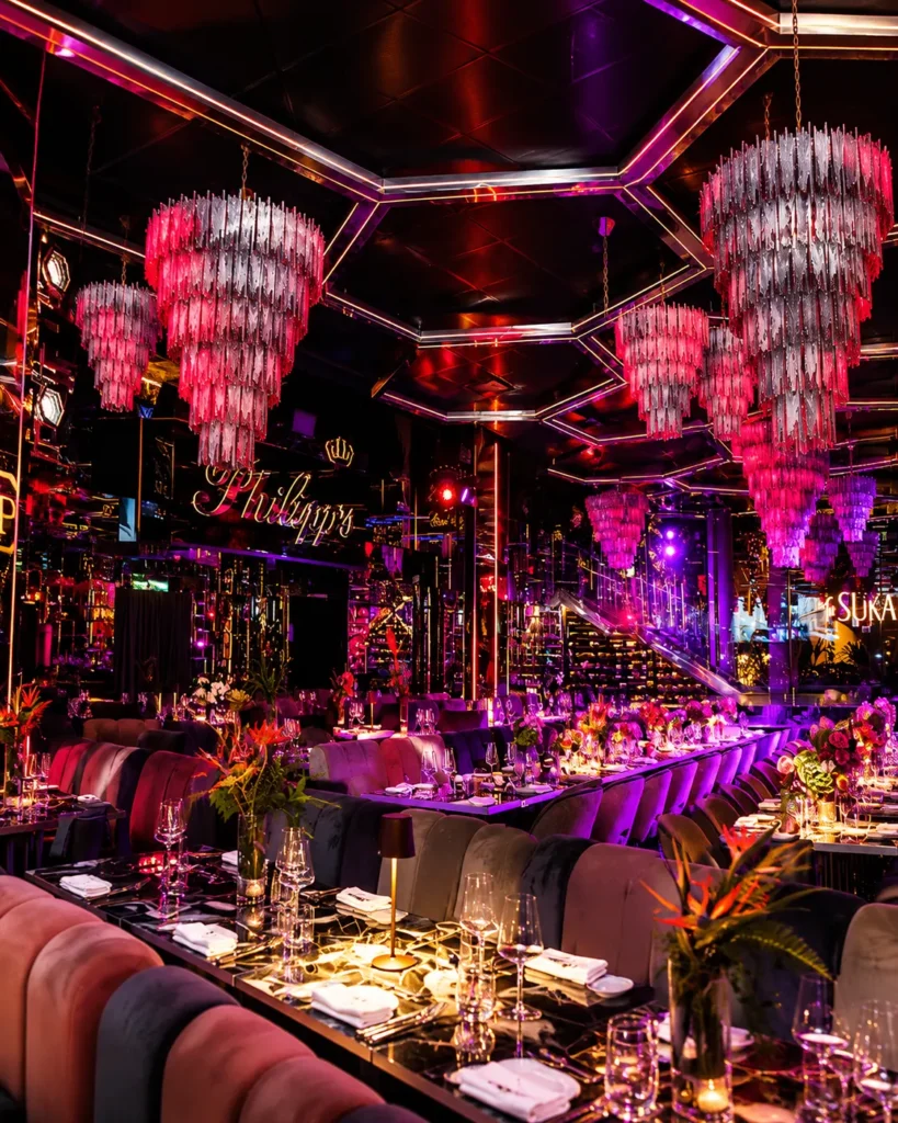 Vibrant dining room with pink neon lighting, decorative chandeliers and elegant restaurant tables at Philipp's Club Milano
