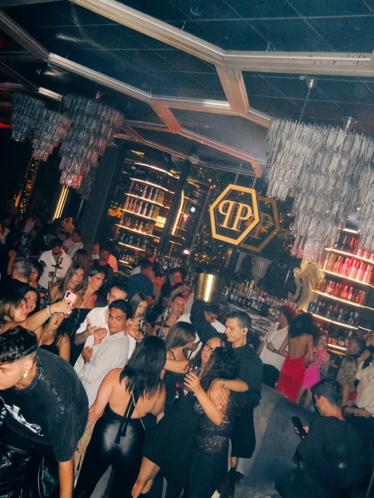 Guests enjoying the lively nightclub atmosphere beneath geometric ceiling lights at Philipp's Club Milano
