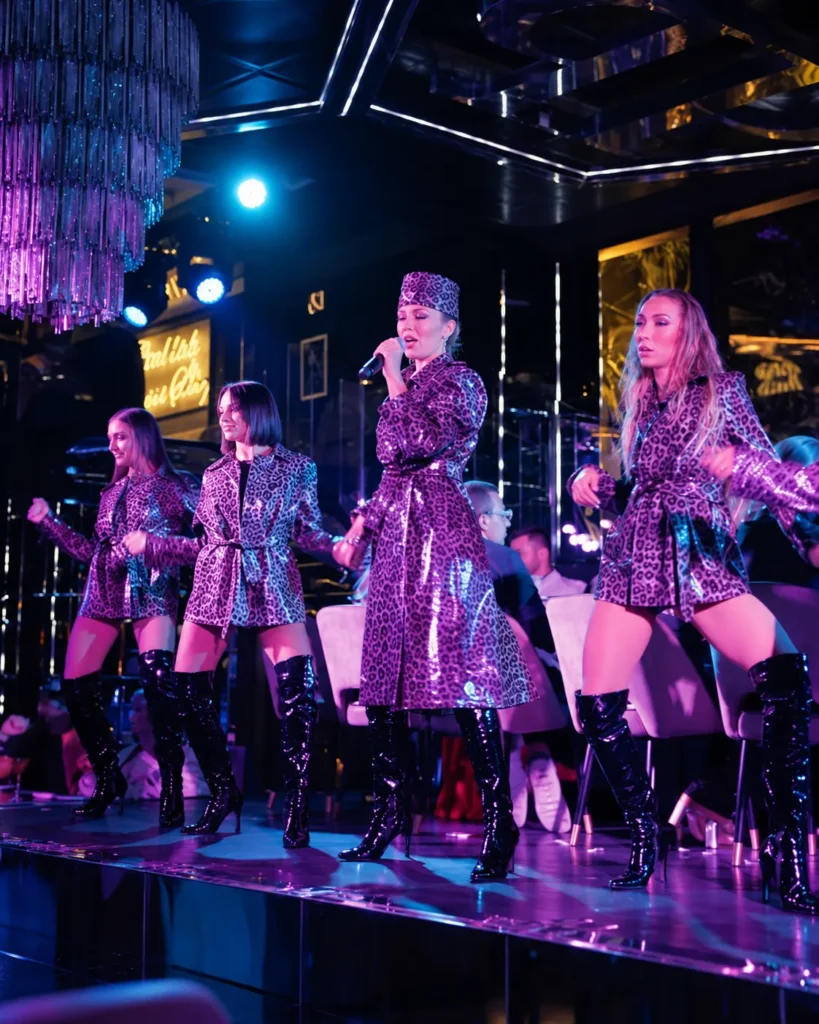 Live performers on stage under vibrant purple and blue lighting at Philipp's Club Milano