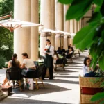 Outdoor restaurant seating beneath tall stone arches with potted greenery at Portrait Milano