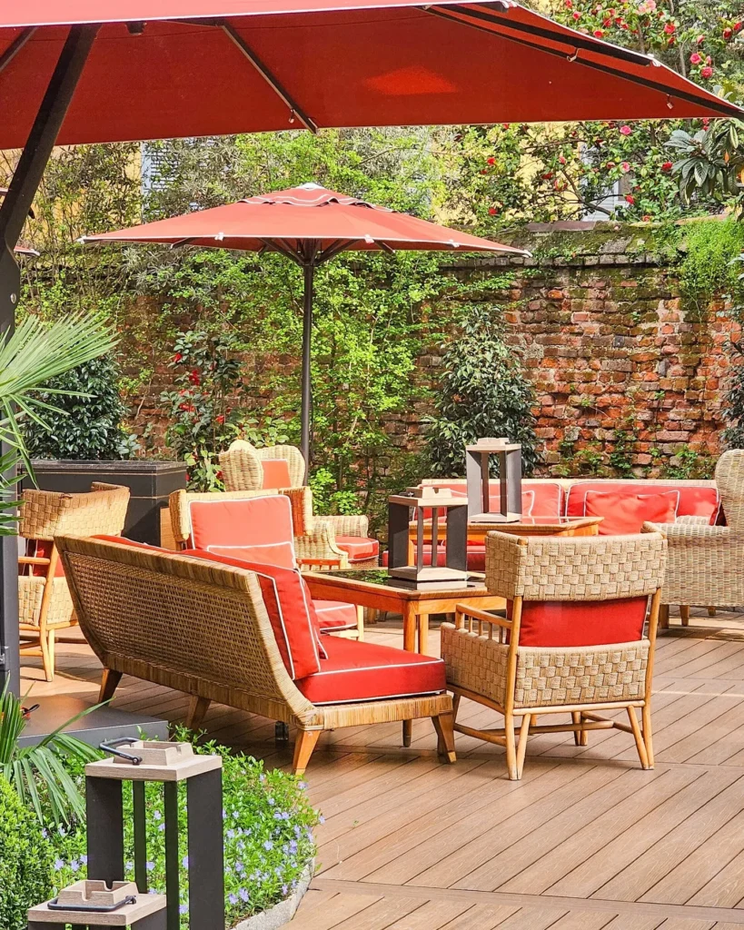 Outdoor lounge terrace with red parasols, comfortable seating and lush greenery at Portrait Milano