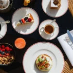 Overhead view of a gourmet tasting menu featuring colorful plated dishes and refined tableware at Portrait Milano