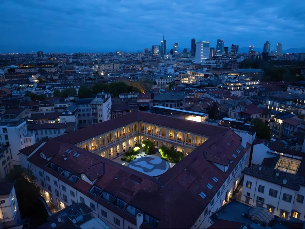 Aerial view of Portrait Milano's historic courtyard complex and surrounding Milan skyline at dusk