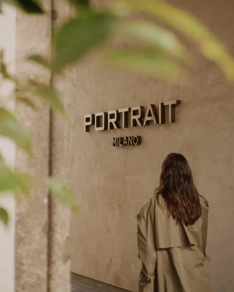 Portrait Milano entrance sign displayed on a textured stone wall beside the hotel doorway