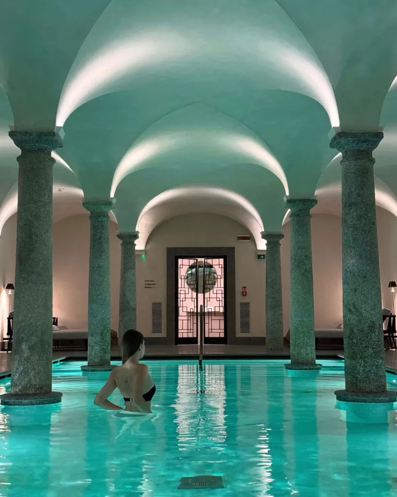 Luxury indoor spa swimming pool with turquoise water, arched ceilings and classical columns at Portrait Milano