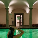 Luxury indoor swimming pool with emerald-green water, arched ceilings and elegant stone columns at Portrait Milano