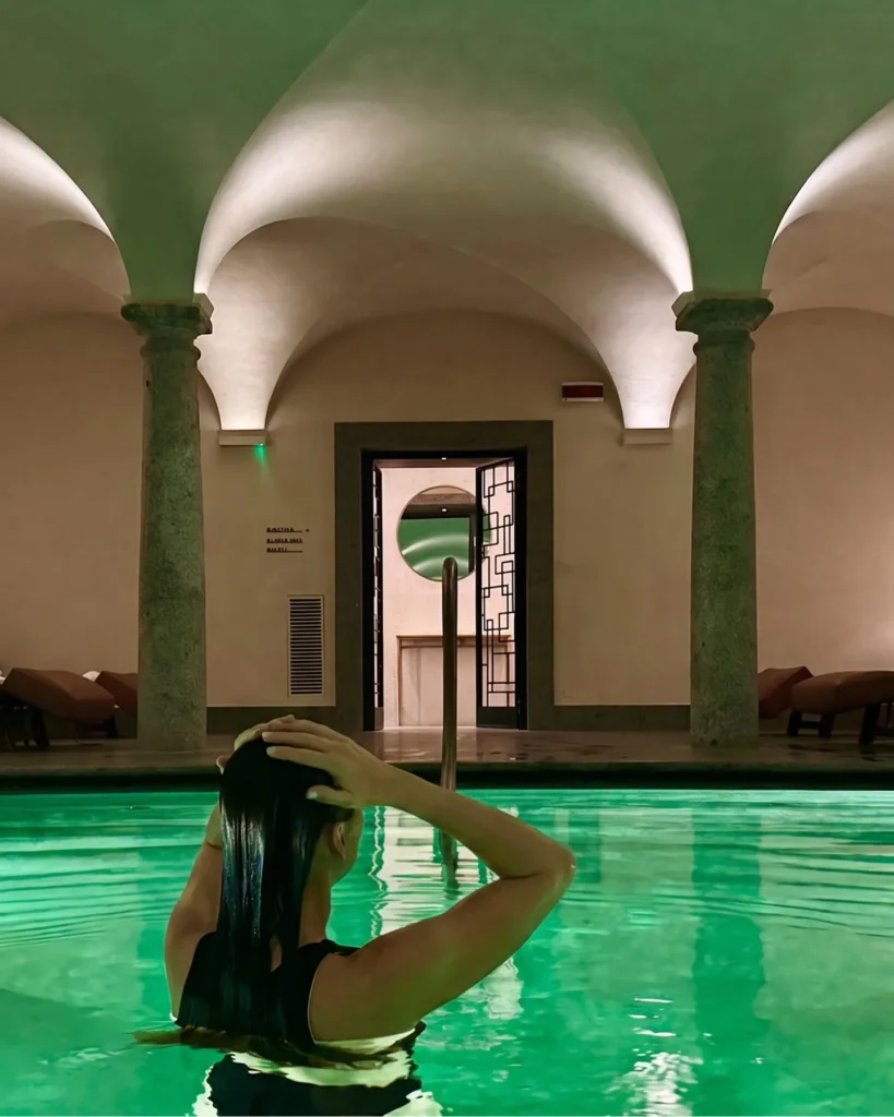 Luxury indoor swimming pool with emerald-green water, arched ceilings and elegant stone columns at Portrait Milano