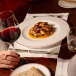 Italian fine dining dish served on a white plate with wine and elegant table settings at Portrait Milano