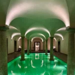 Serene spa pool beneath illuminated vaulted arches at Portrait Milano with turquoise water and classical architectural details