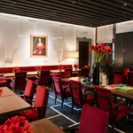 Elegant restaurant interior with red upholstered chairs, white tablecloths and contemporary artwork at Portrait Milano