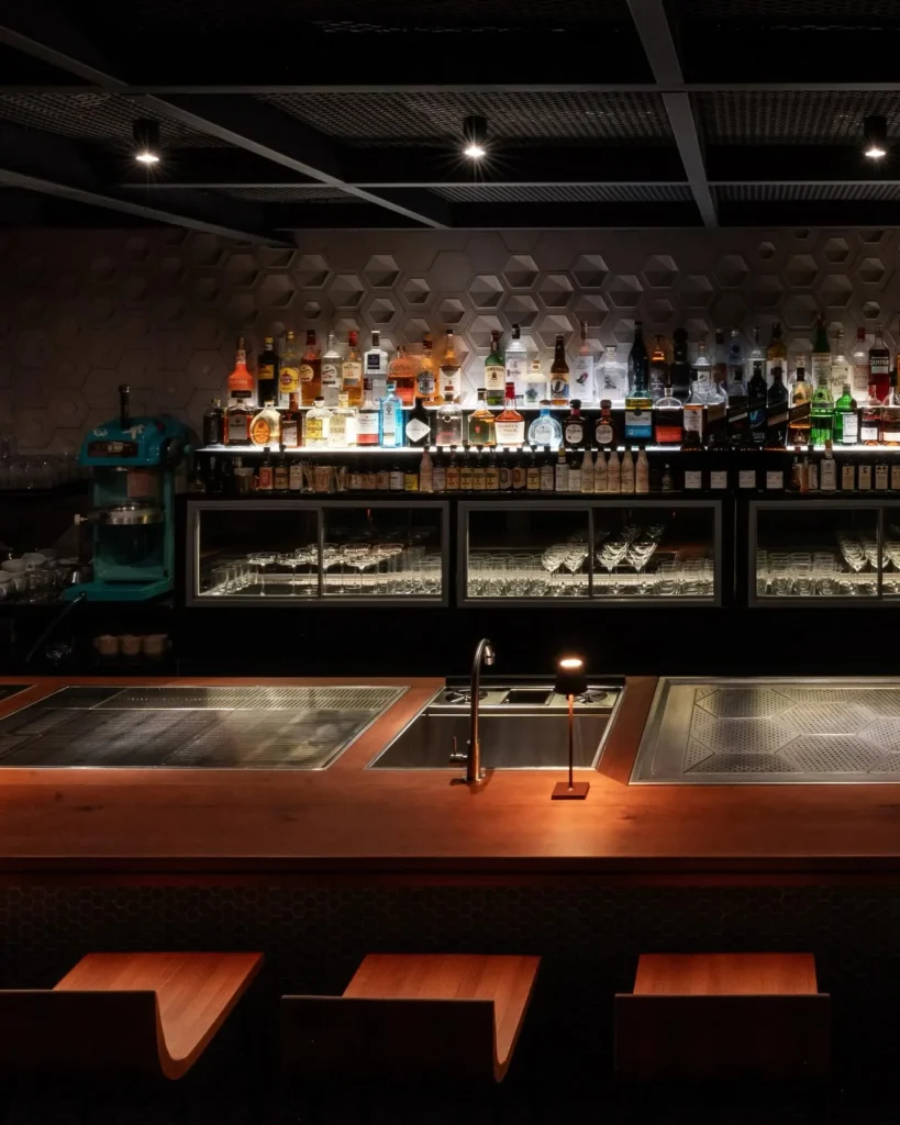 Atmospheric hotel bar with a backlit display of bottles and a dark elegant interior at Rosewood Hôtel de Crillon