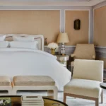 Elegant hotel bedroom with white linens and classic neutral furnishings at Rosewood Hôtel de Crillon Paris