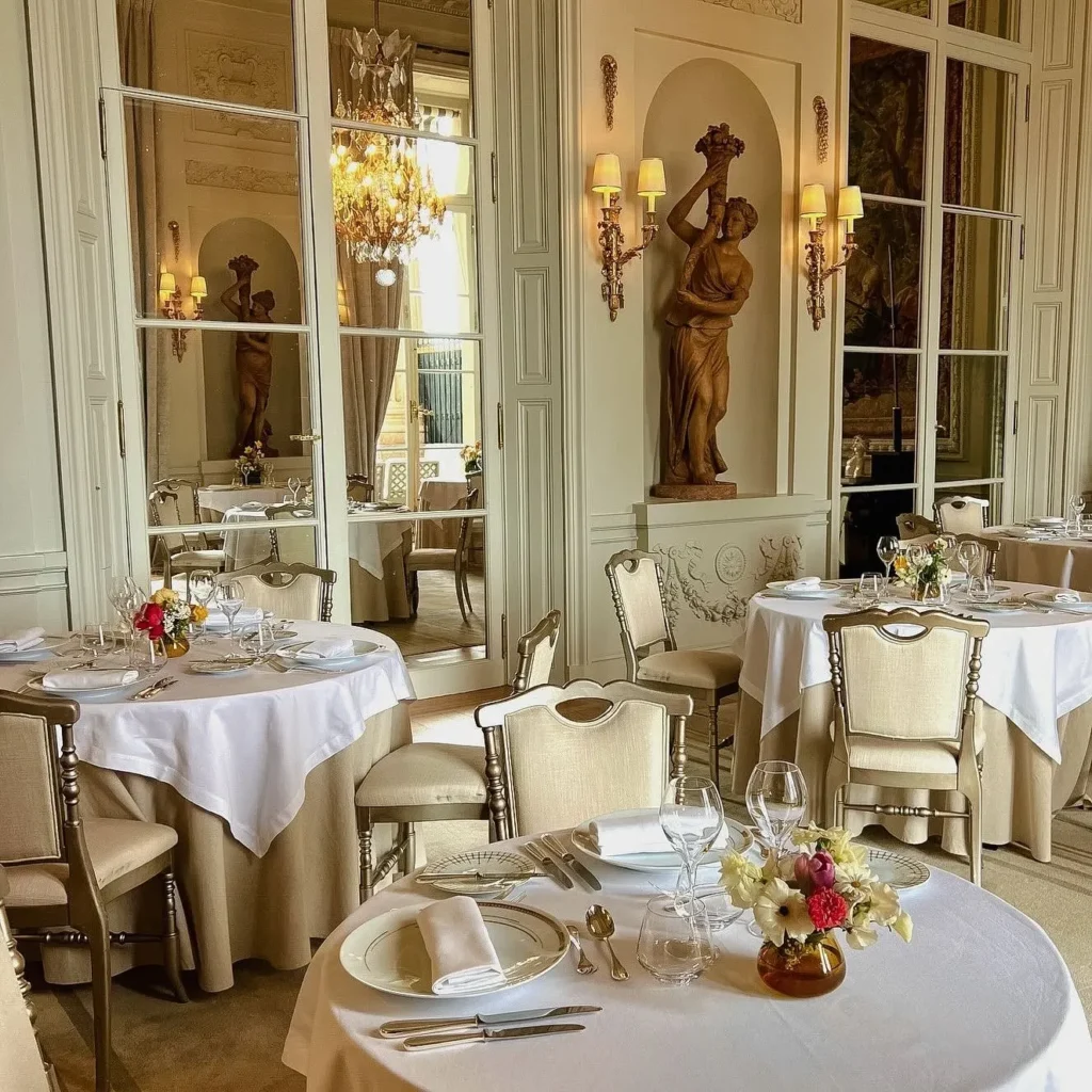 Elegant restaurant interior with white tablecloths, classic French decor and ornate architectural details at Rosewood Hôtel de Crillon Paris
