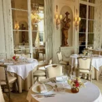 Elegant restaurant interior with white tablecloths, classic French decor and ornate architectural details at Rosewood Hôtel de Crillon Paris
