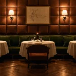 Elegant candlelit dining lounge at The Carlton Milan featuring velvet seating, white tablecloths, and warm wall lighting