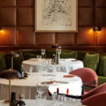 Elegant restaurant table at The Carlton Milan set with white tableware, glassware, and fine dining accessories in a warm, refined interior