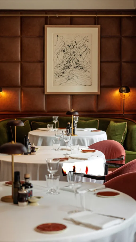 Elegant restaurant table at The Carlton Milan set with white tableware, glassware, and fine dining accessories in a warm, refined interior