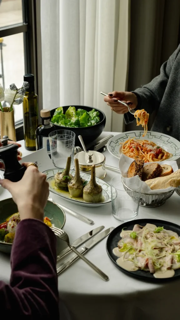Fine dining experience at The Carlton Milan with beautifully presented dishes, glassware, and elegant table settings beside a window
