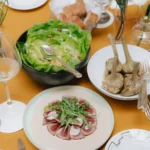 Overhead view of a gourmet meal at The Carlton Milan featuring several colorful dishes arranged across a dining table