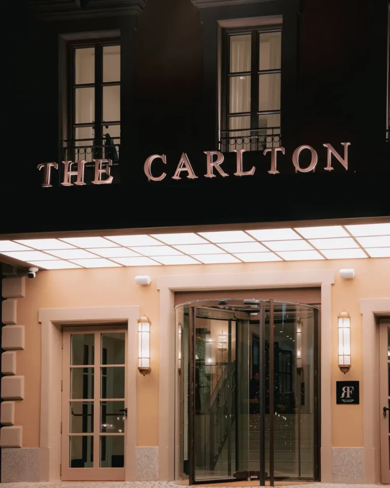The Carlton Milan hotel sign above the entrance, set against a dark facade and elegant stone exterior
