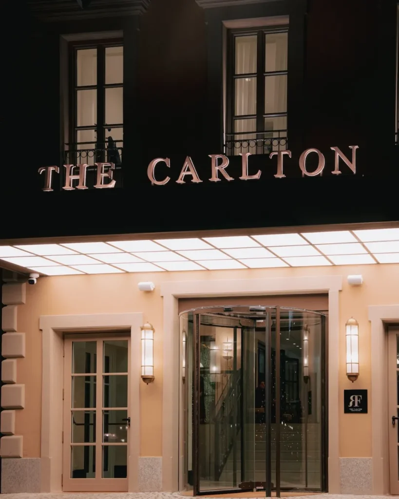 The Carlton Milan hotel sign above the entrance, set against a dark facade and elegant stone exterior