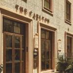 Street-level exterior of The Carlton Milan featuring elegant stone architecture, large windows, and the hotel's entrance