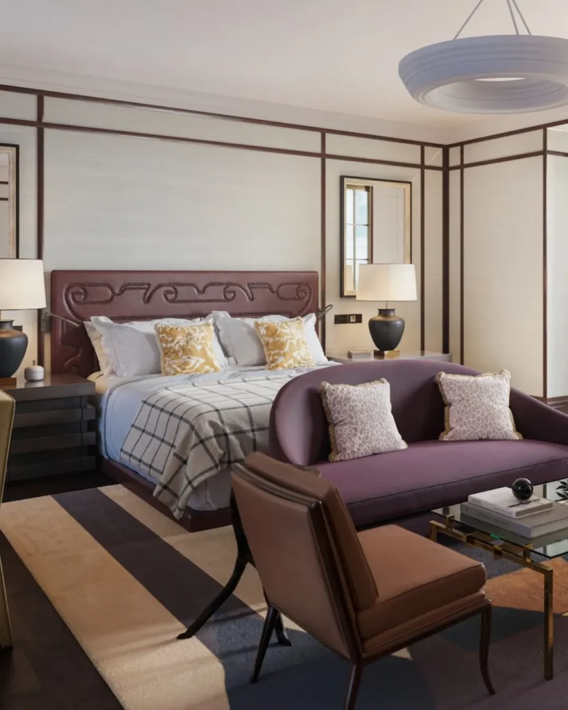 Luxury guest bedroom at The Carlton Milan featuring a plush bed, muted pink and cream tones, elegant artwork, and a comfortable armchair