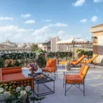 Scala Suite terrace at The Carlton Milan with colorful lounge chairs, landscaped planters, and views over Milan rooftops